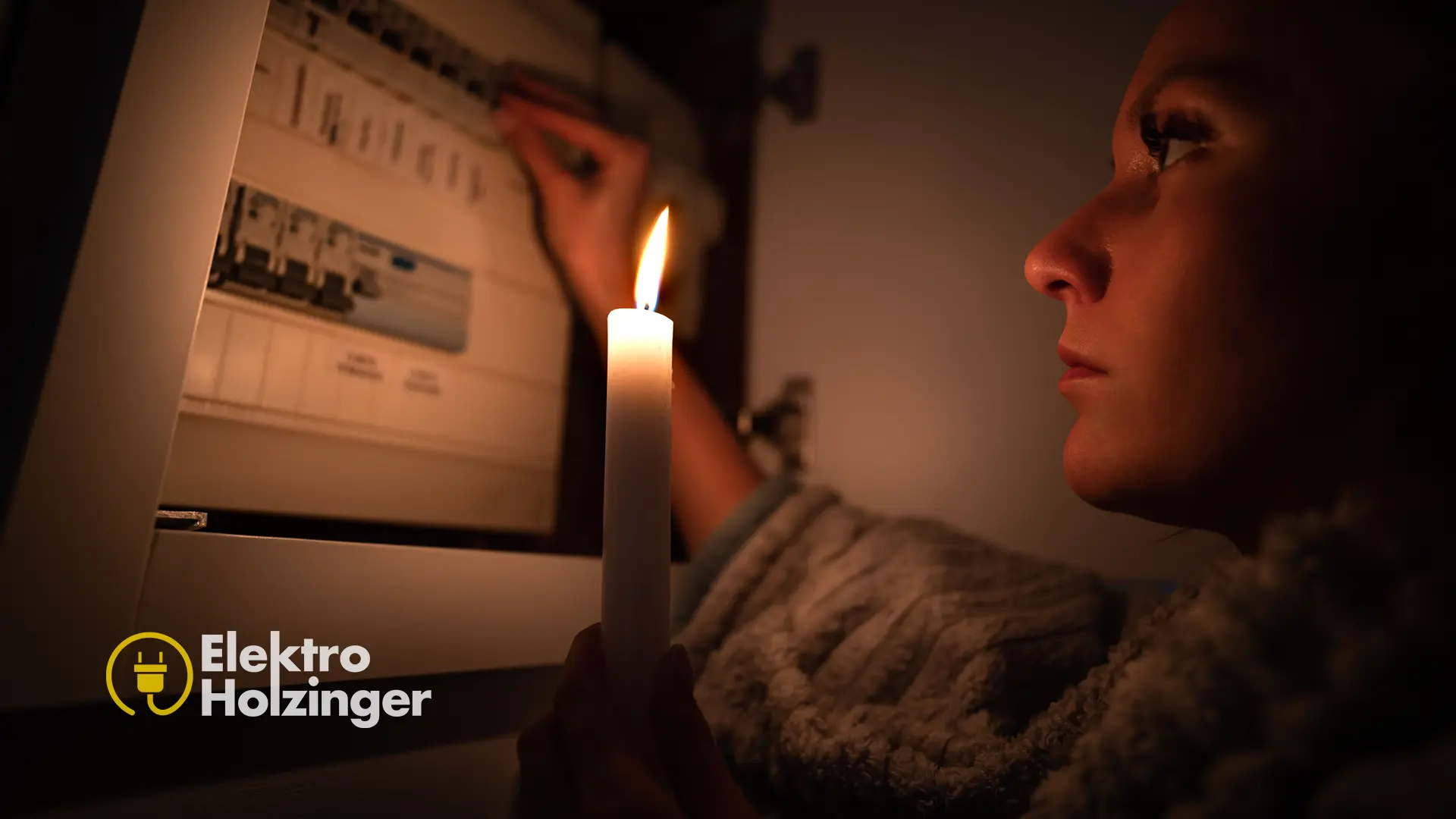 Frau sucht mit einer Kerze im Dunkeln nach der Fehlerquelle im Sicherungskasten bei einem Stromausfall – Störungsdienst Elektro Holzinger